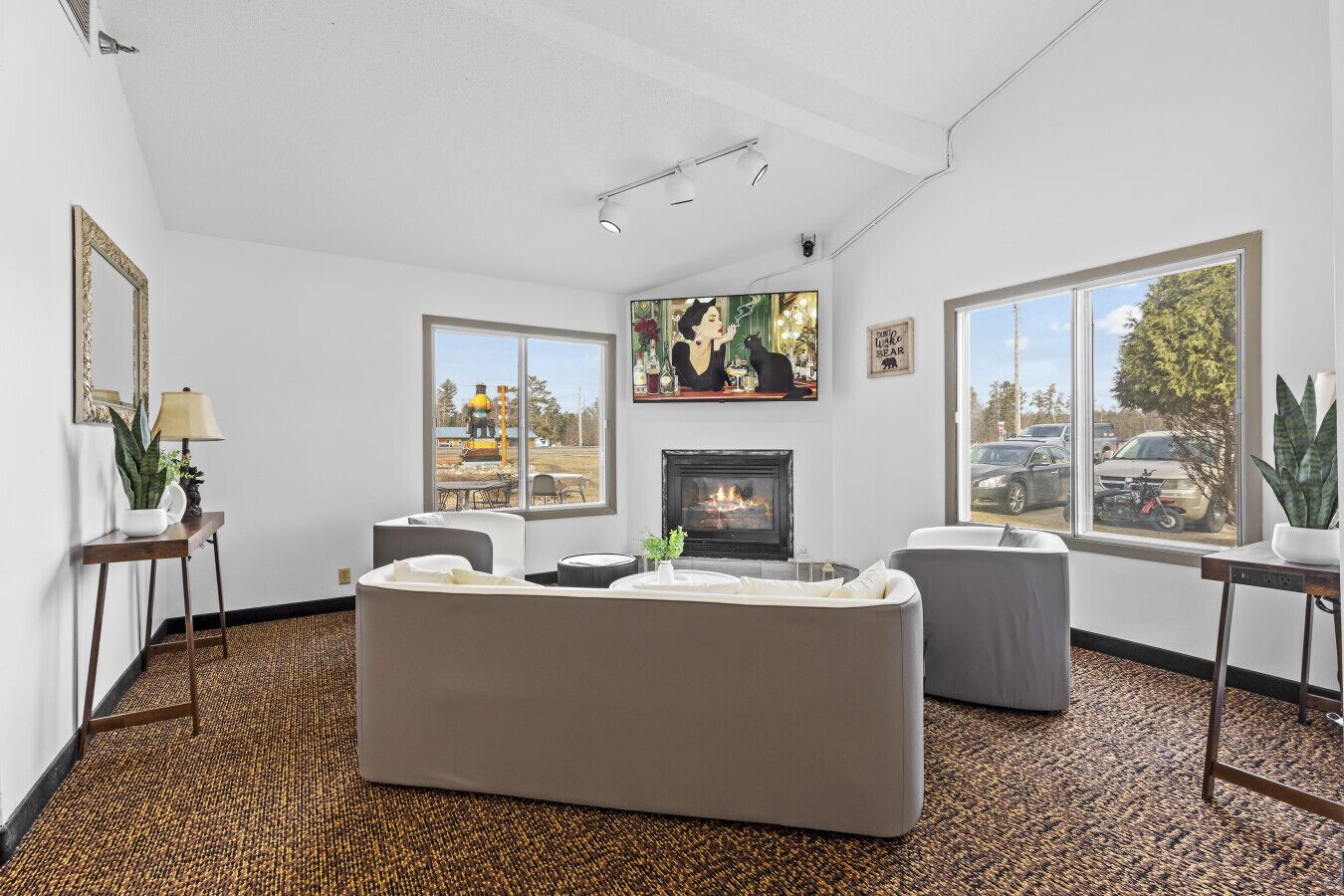 A living room with a fireplace, two sofas, a coffee table, a large window, and a painting on the wall.