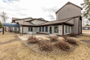 A modern two-story house with a covered patio, large windows, and a stone foundation.