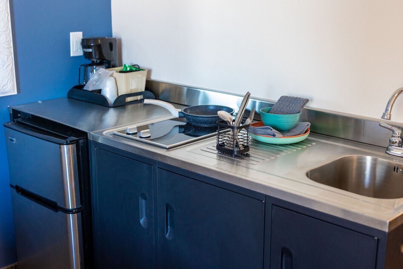A compact kitchen with a built-in oven, a coffee maker, and a sink.