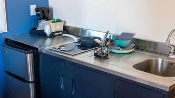 A compact kitchen with a built-in oven, a coffee maker, and a sink.