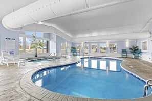 Ein Schwimmbecken mit geschwungenem Design, umgeben von Liegestühlen und Kübelpflanzen.