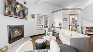 A modern living room with a fireplace, white sofas, a coffee table, and a painting on the wall. - Nisswa Hotel & Suites – Cullen Lake Jacuzzi King (Nisswa)