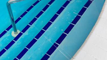 Una piscina con escalones de cerámica azul y blanca y una barandilla de metal.