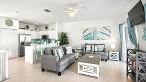 A spacious living area with a grey sofa, a coffee table, and a TV mounted on the wall. - Beach and Bay Bliss at Bermuda Bay Club/Poolside (Bradenton Beach)