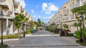 A residential street with multi-story buildings, paved sidewalks, and palm trees. - Beach and Bay Bliss at Bermuda Bay Club/Poolside (Bradenton Beach)