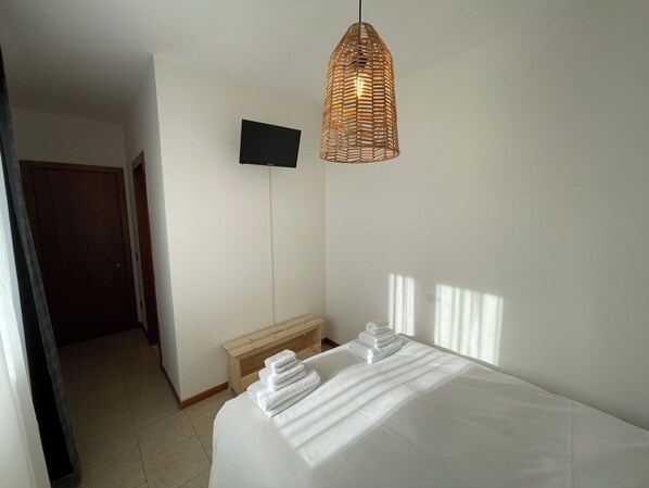 A bedroom with a bed, a television mounted on the wall, and a hanging light fixture. - Albergaria (Rossano Veneto)
