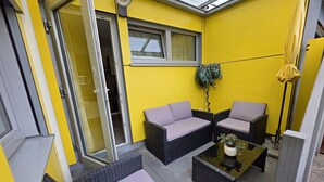 Ein sonnendurchflutetes Zimmer mit Korbmöbeln, einer Glastür und einem Blumentopf.