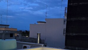 A rooftop terrace with a modern design, featuring a flat surface and a few steps leading up to a seating area.