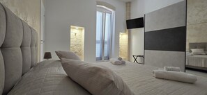 Une chambre moderne avec un grand lit, un téléviseur à écran plat et un mur en pierre.