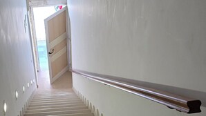 A staircase with a handrail, leading to a door at the top.