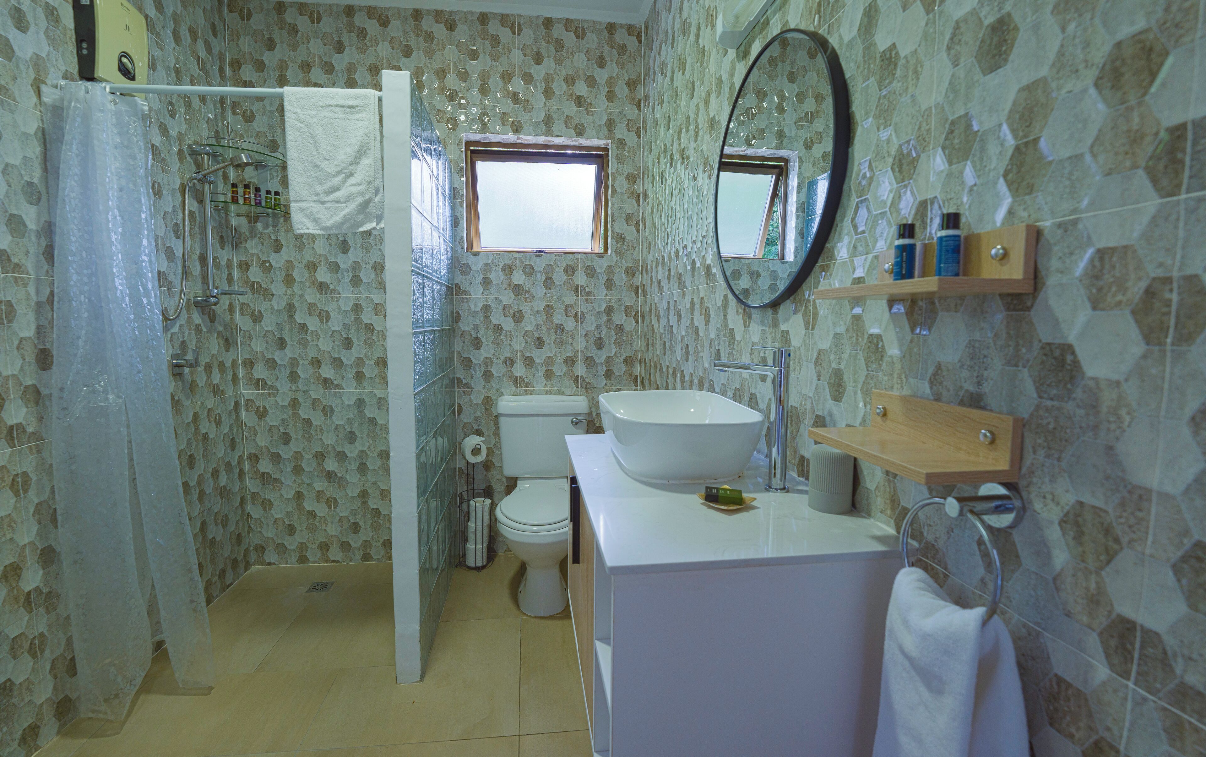 Une salle de bain équipée d’une douche, de toilettes, d’un lavabo et d’un miroir.