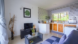 Un salon moderne avec un canapé, un téléviseur et une table basse en verre.