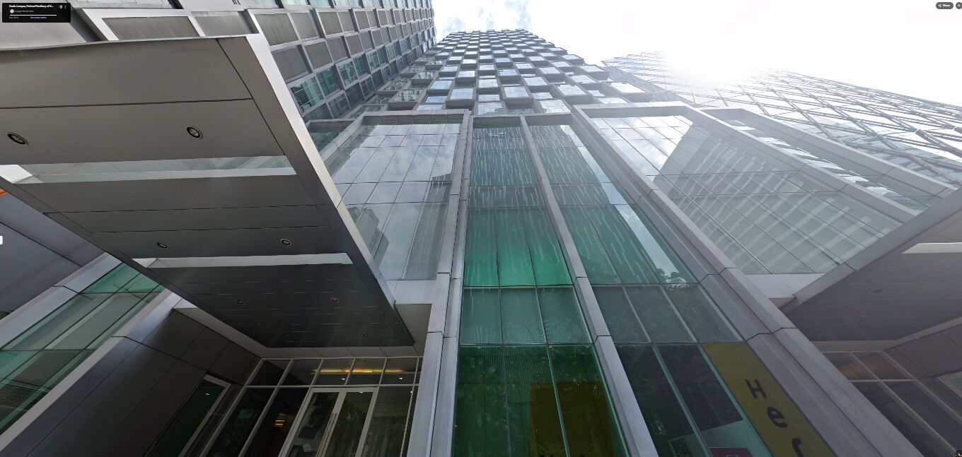 Un immeuble moderne de grande hauteur, doté d’une façade en verre et d’un logo en forme de « H » bien visible sur le côté.
