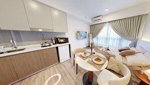 A modern hotel room with a kitchenette, a dining area with a table and chairs, a bed with a view, and a large window with curtains. - SOHO Suites KLCC by noon (Kuala Lumpur)