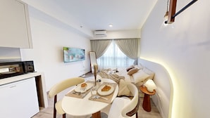 A modern hotel room with a dining area, a kitchenette, and a bed with a view. - SOHO Suites KLCC by noon (Kuala Lumpur)