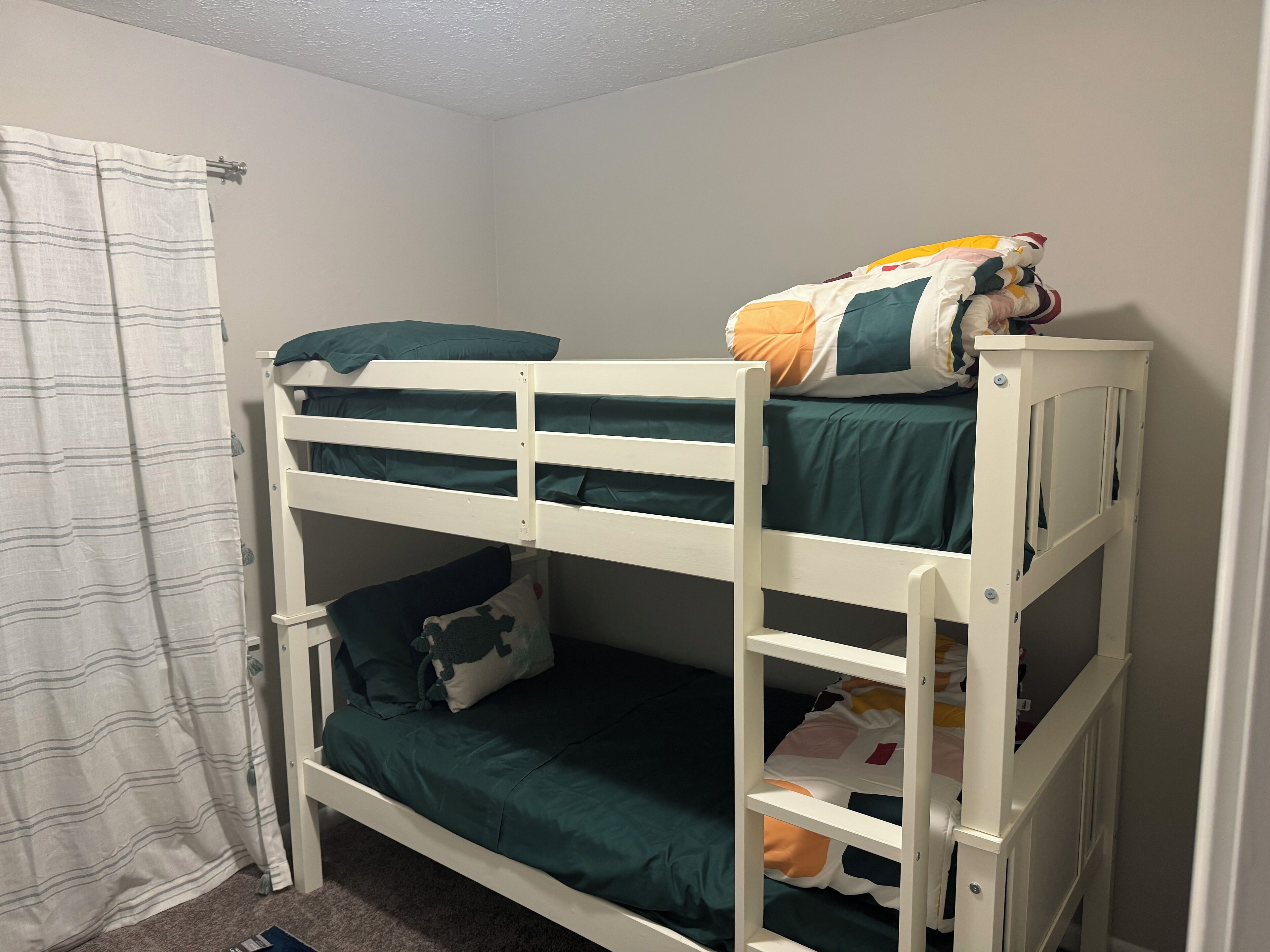 Un lit superposé à deux niveaux, chaque niveau étant équipé d’un matelas et d’oreillers.