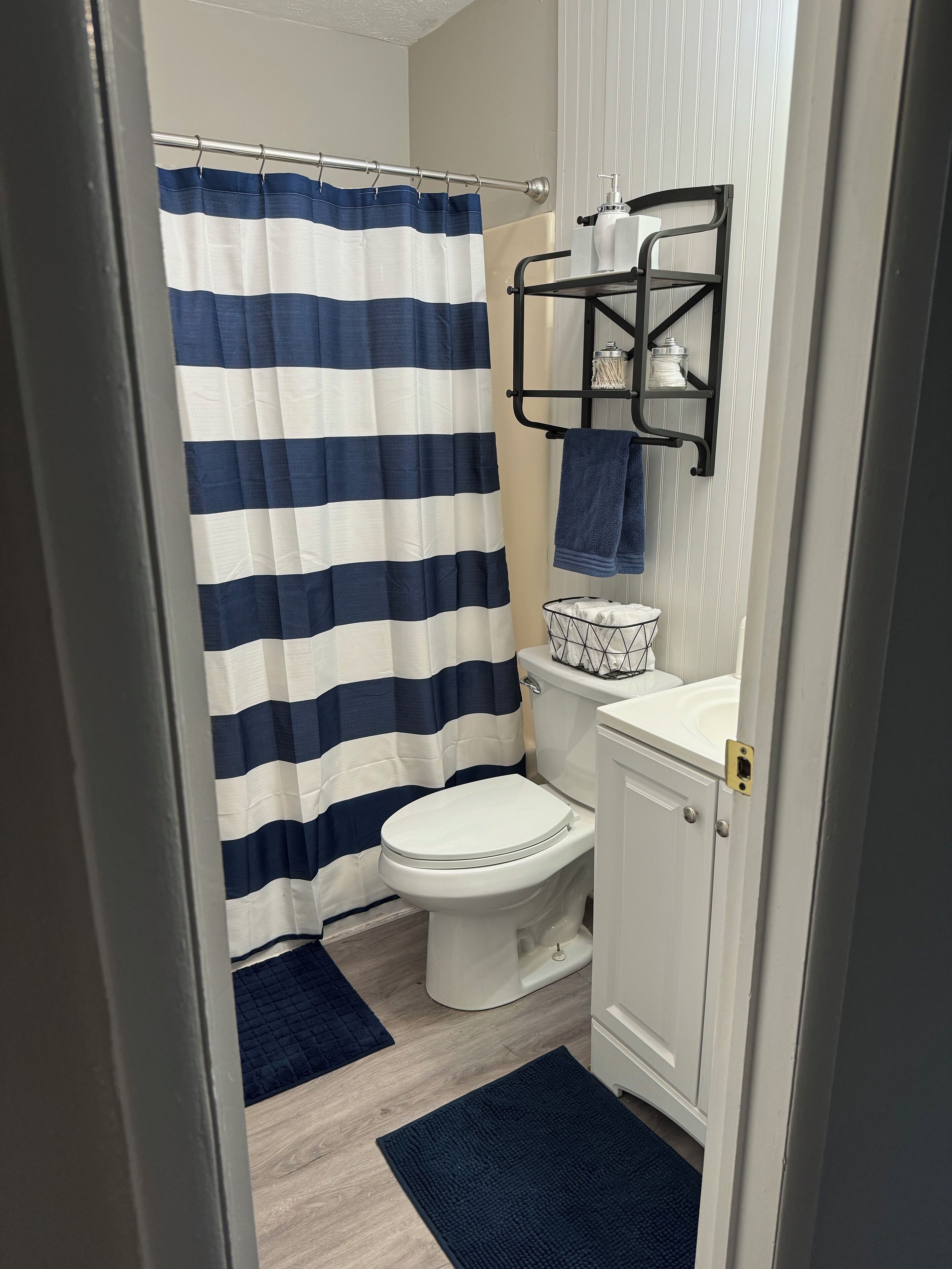 Une salle de bain avec un rideau de douche à rayures, des toilettes, un lavabo et un porte-serviettes.