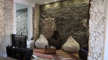 A living room with a stone wall, a television, bean bags, and a coffee table.