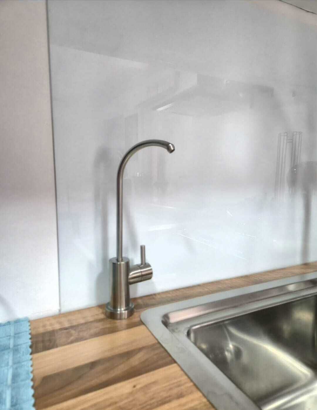 Een keuken met een RVS spoelbak, een houten werkblad en een moderne kraan.