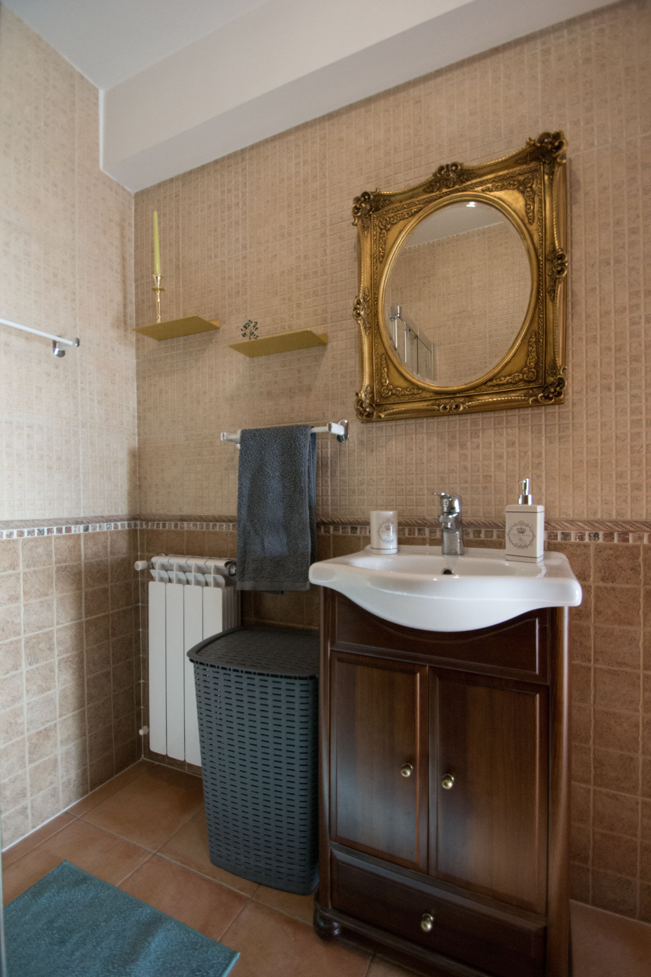 A bathroom with a sink, mirror, towel rack, and radiator.