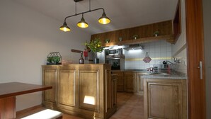Una cocina con armarios de madera, una isla central, una mesa de comedor y un colgador de luz.