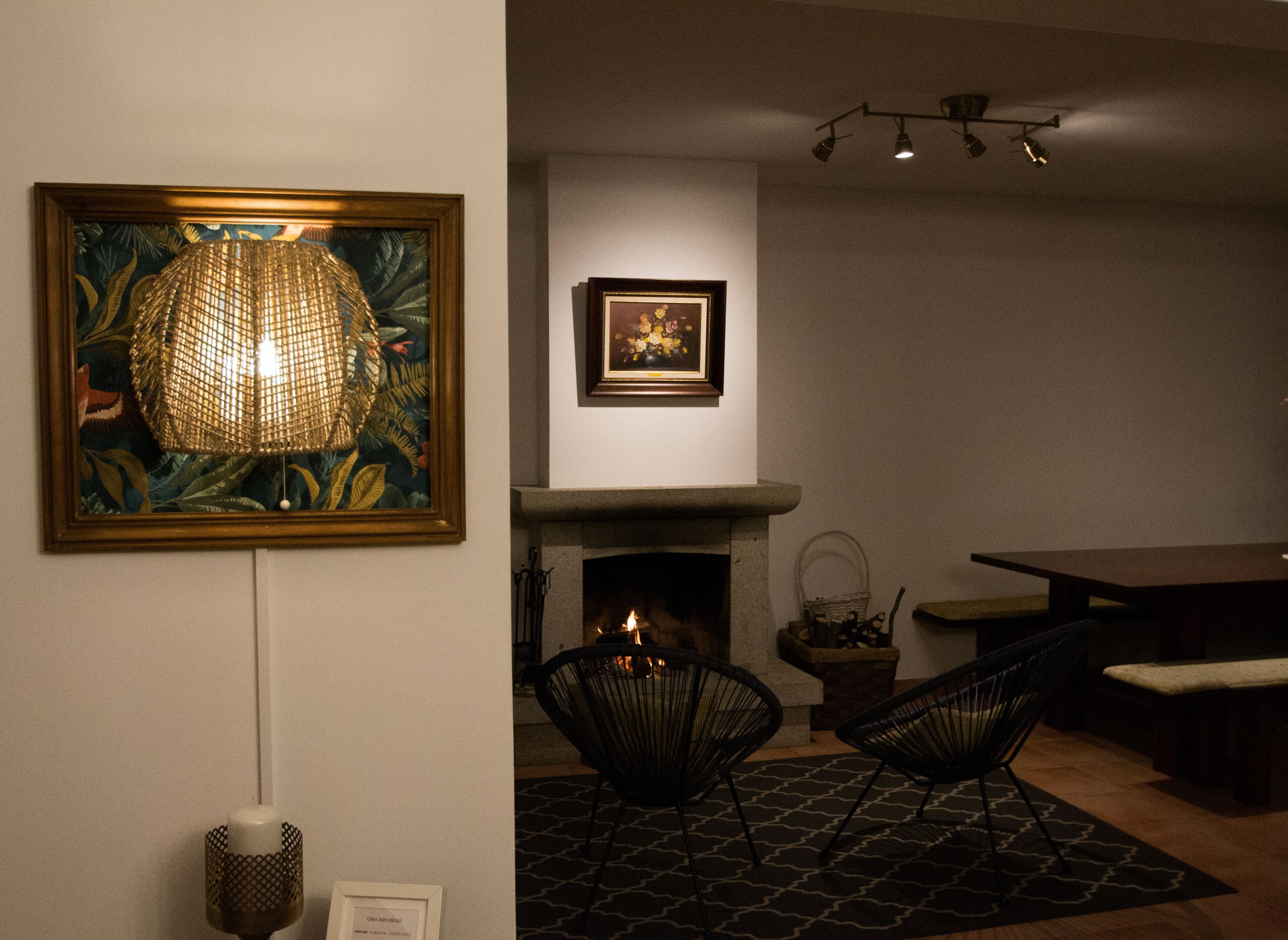 Una habitación con chimenea, dos sillones, una mesa de comedor y dos cuadros en la pared.