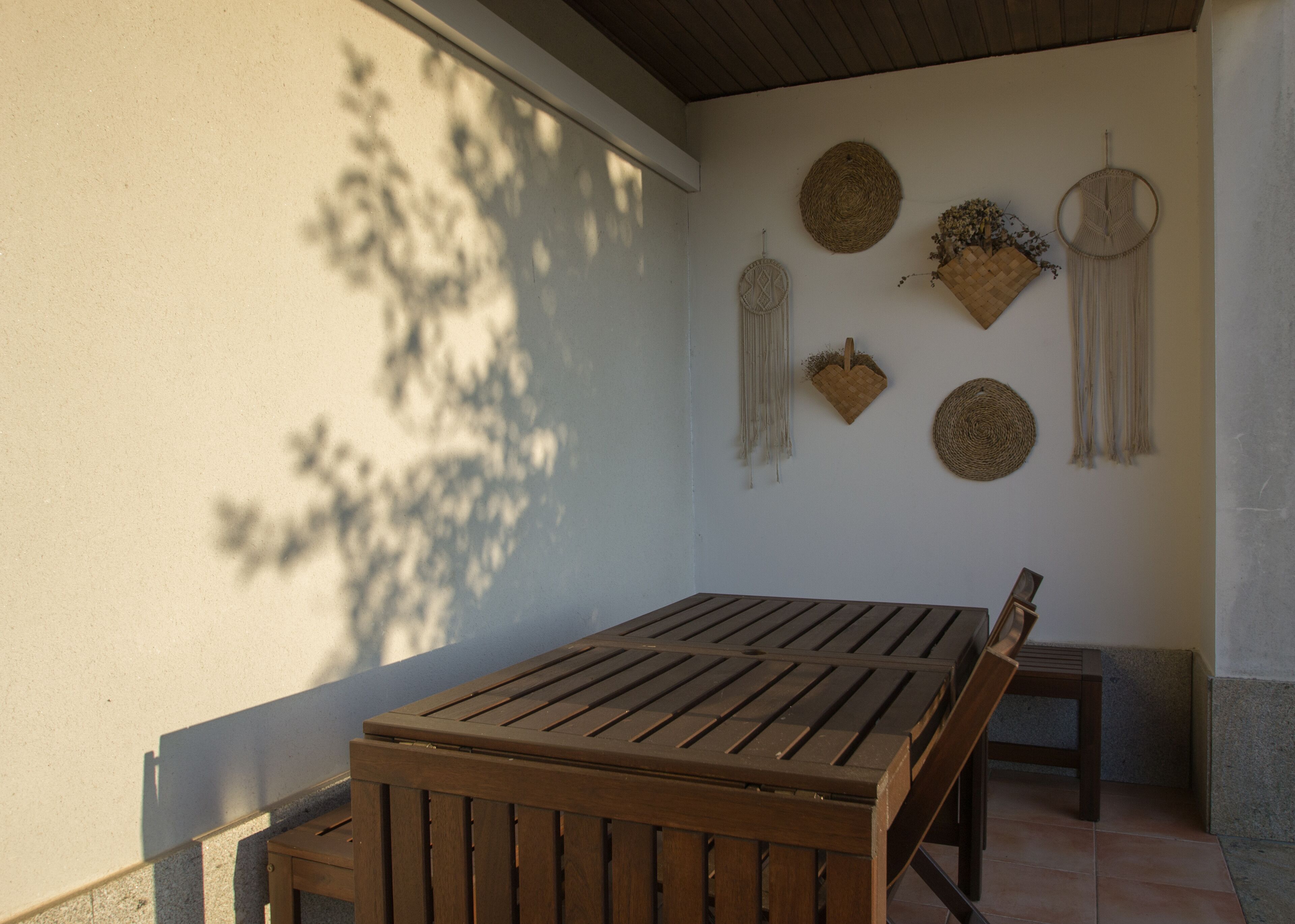 Une table et un banc en bois, placés sous un espace ombragé, agrémentés de décorations murales.