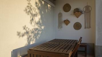 Une table et un banc en bois, placés sous un espace ombragé, agrémentés de décorations murales.