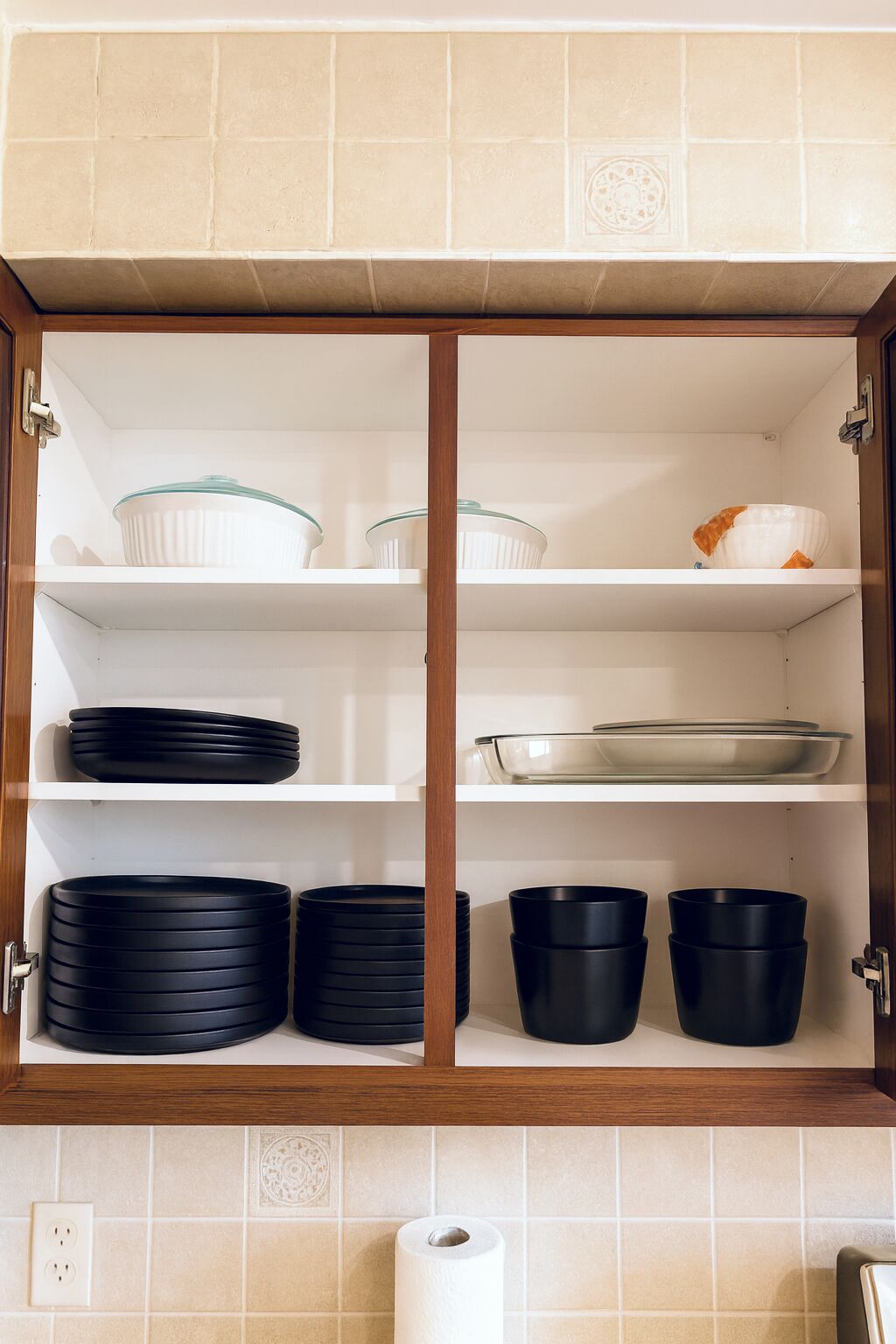 A kitchen cabinet with shelves holding various dishes and cookware.