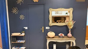 A dark blue door with a gold-framed mirror, a shelf with decorative items, and a small table with a vase and a lamp. - Charming Solognese house for 4 people (Pierrefitte-sur-Sauldre)