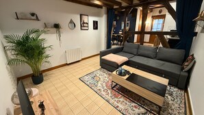 A cozy living room with a dark grey sofa, a wooden coffee table, and a large potted plant. - Charming Solognese house for 4 people (Pierrefitte-sur-Sauldre)