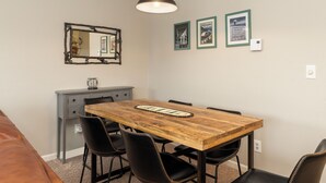 Een eetgedeelte met een houten tafel, zwarte stoelen, een spiegel en lijstjes met foto's aan de muur.