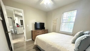 A bedroom with a bed, a television on a wooden dresser, and a window with blinds. - Clean, Bright & Peaceful home in quiet neighborhood close proximity to FSU &FAMU (Tallahassee)