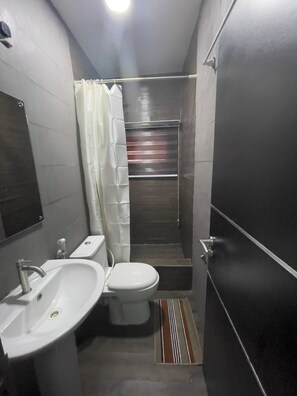 Une petite salle de bain avec un lavabo blanc, des toilettes et une cabine de douche.