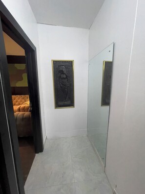 Un couloir étroit avec un mur recouvert de miroirs, une œuvre d’art encadrée et un canapé capitonné en arrière-plan.
