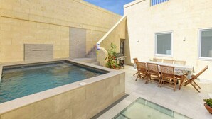 Una piscina con idromassaggio, area relax all'aperto e una scala che conduce a un balcone.