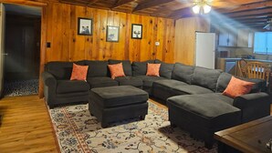 Una sala acogedora con un sofá seccional, otomanas y una alfombra estampada.