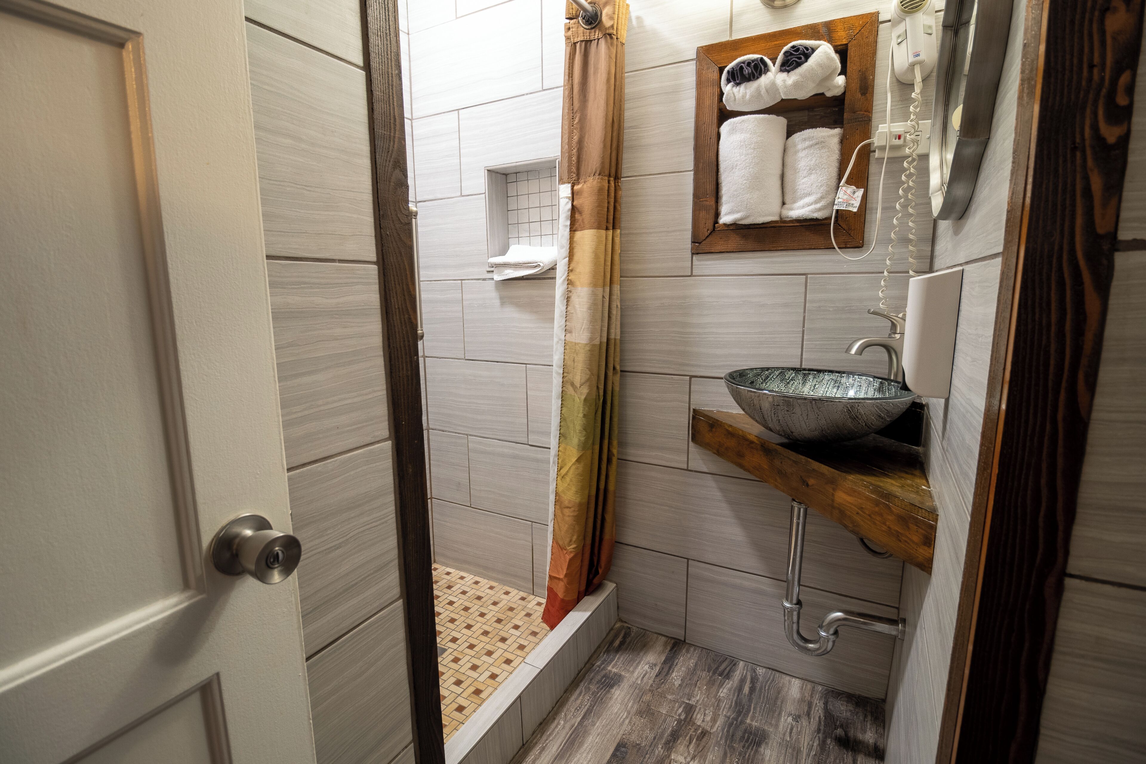A bathroom with a shower, a sink with a bowl, and a towel rack.