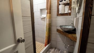 A bathroom with a shower, a sink with a bowl, and a towel rack.