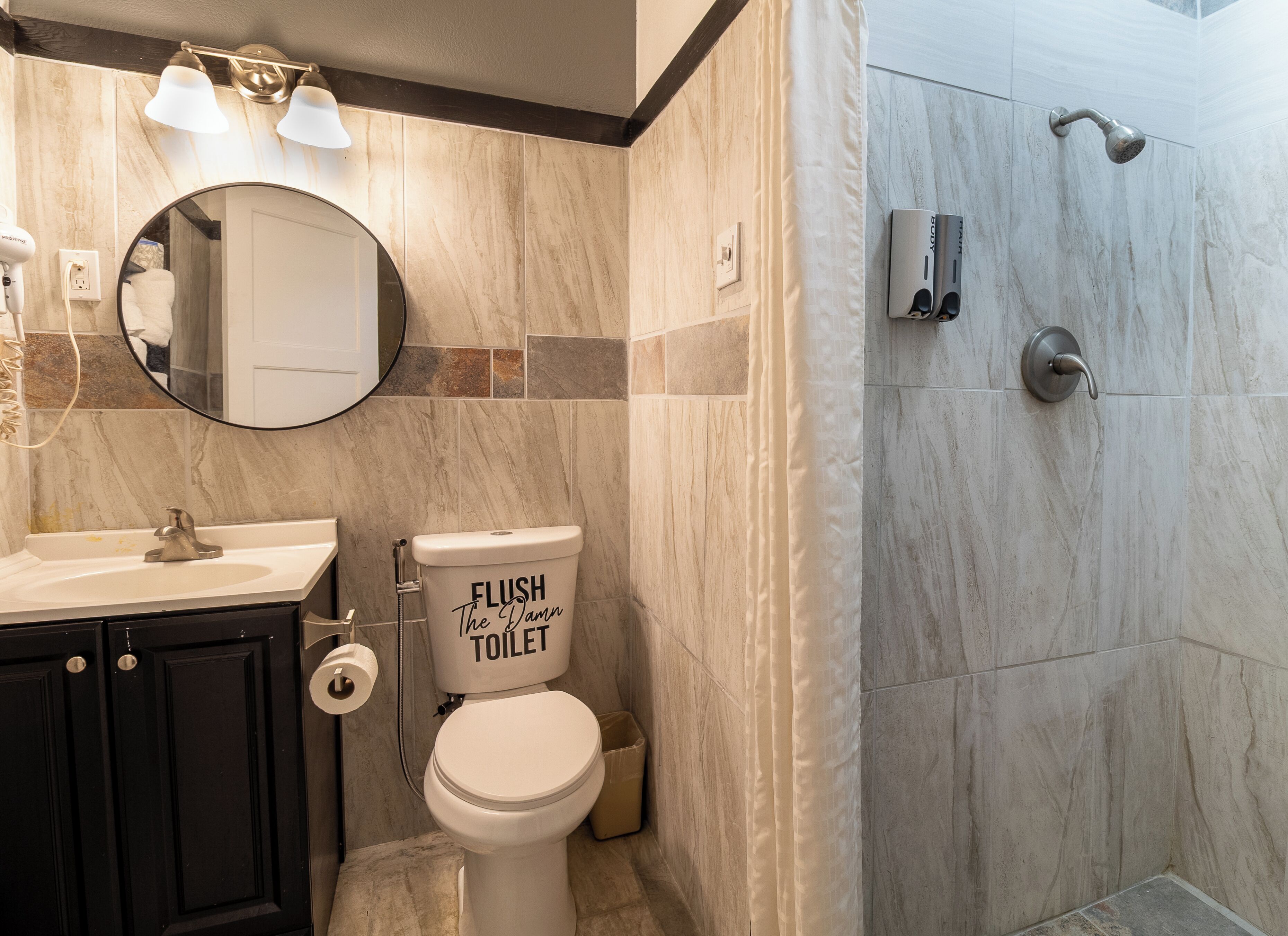 A bathroom with a toilet, sink, mirror, and shower.