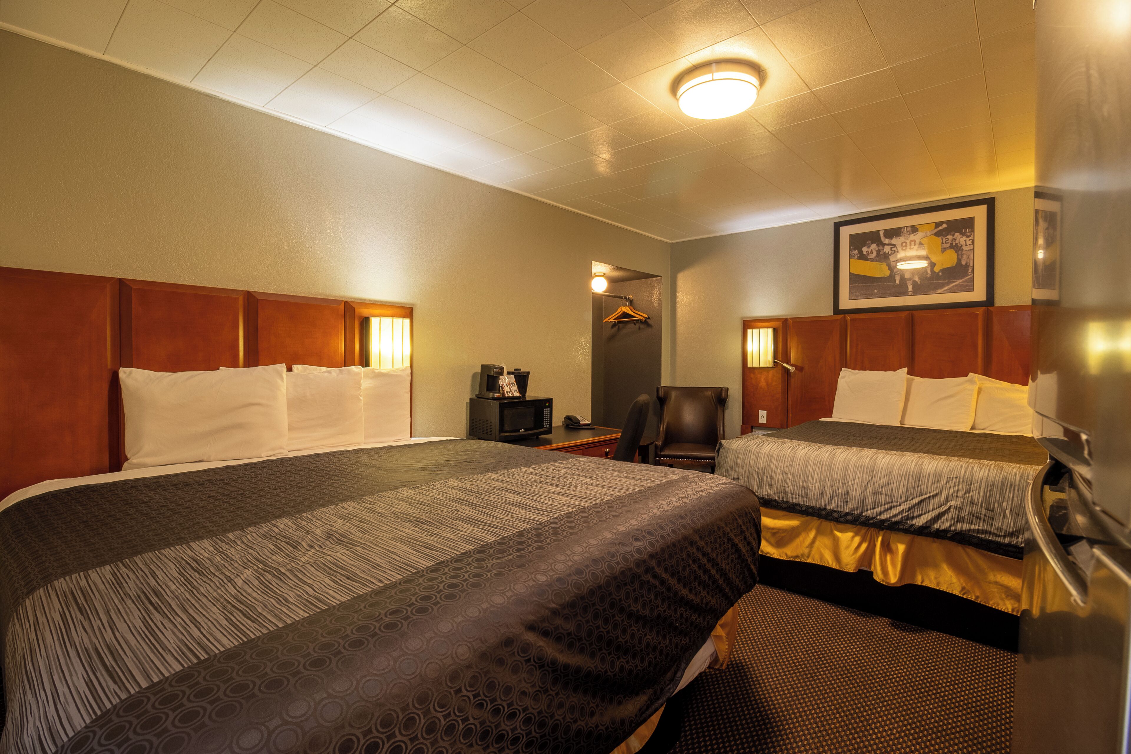 A hotel room with two beds, a desk with a computer, a chair, and a framed picture on the wall.