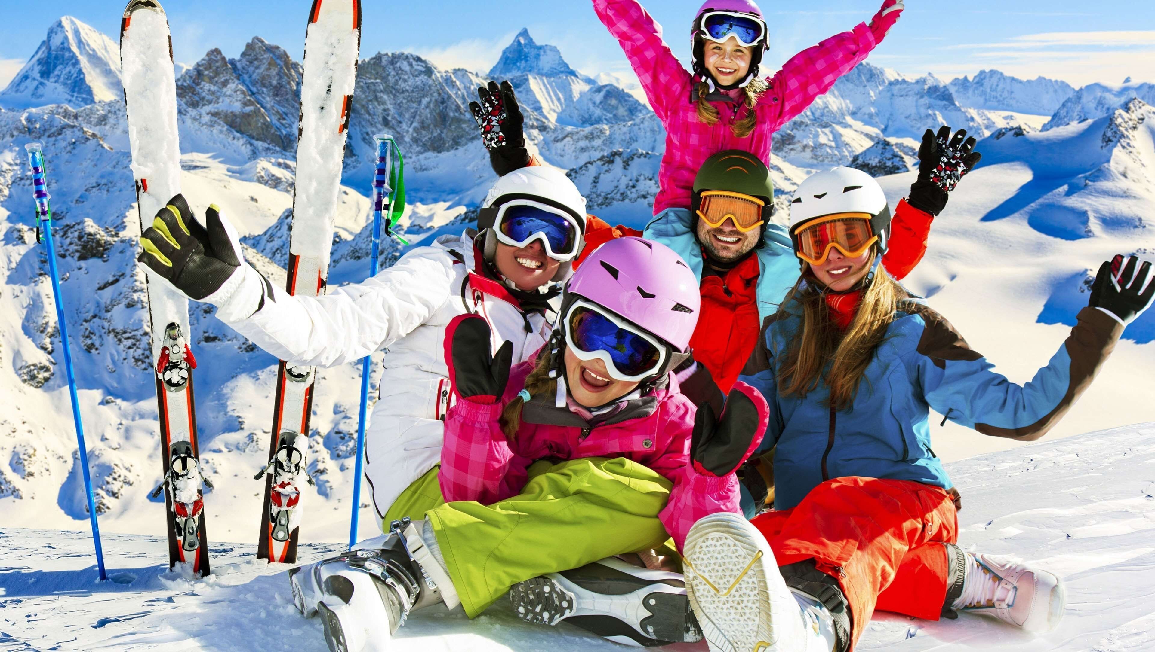A group of people on a snowy mountain with skis and snowboards, indicating a ski resort.