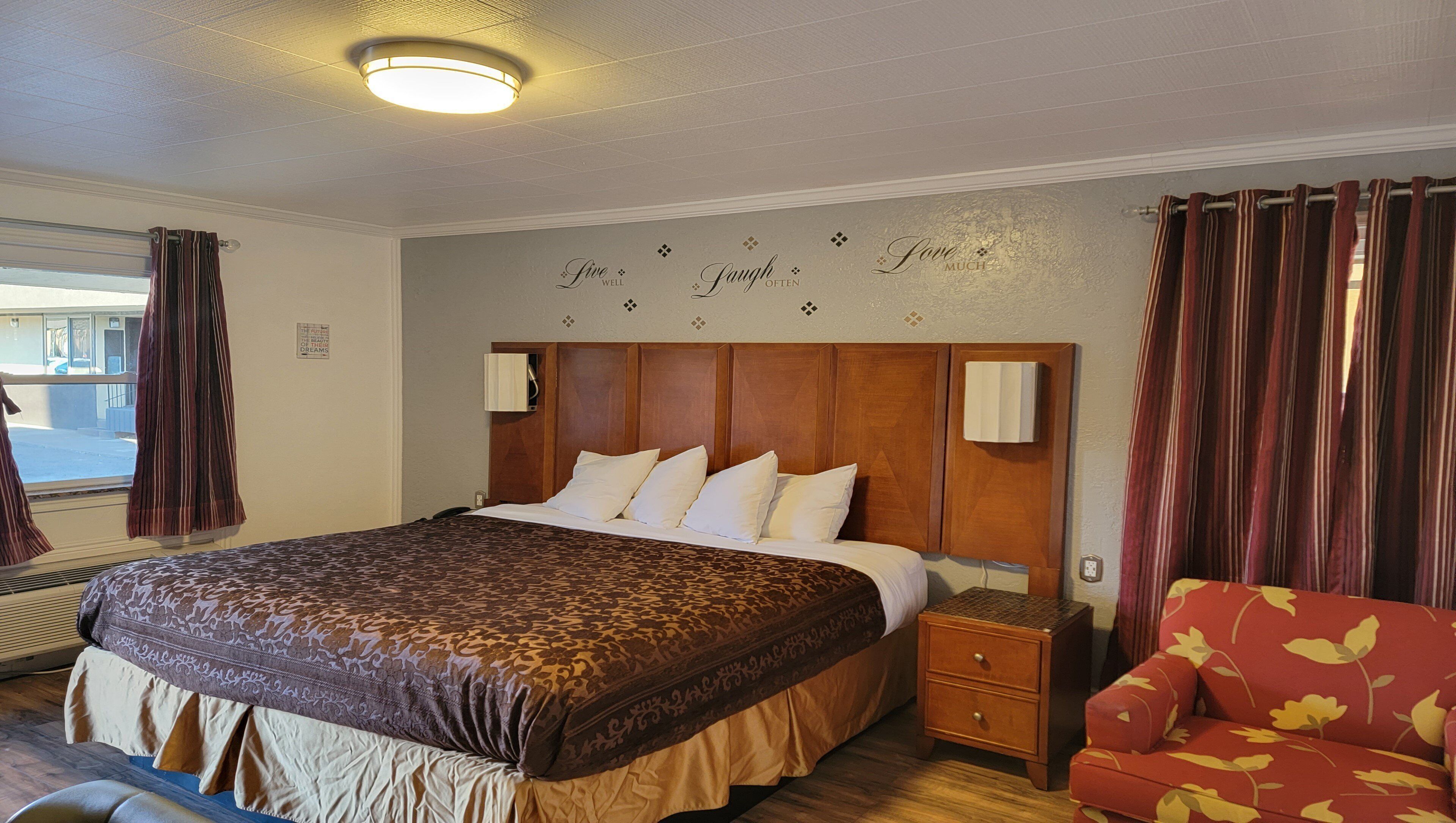 Une chambre d’hôtel avec un grand lit, une table de chevet, une chaise et un mur orné de citations inspirantes.