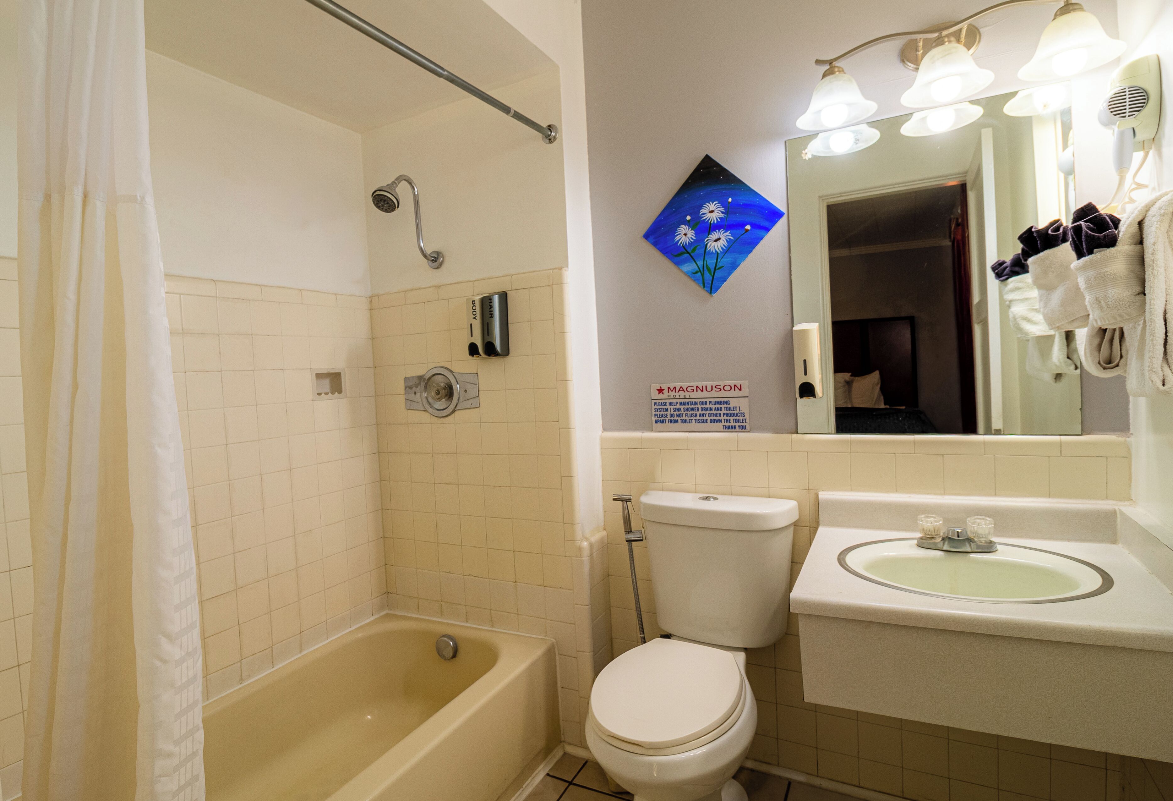 Ein Badezimmer mit einer Badewanne, Toilette und Waschbecken. Ein Handtrockner und ein Handtuchhalter sind vorhanden.
