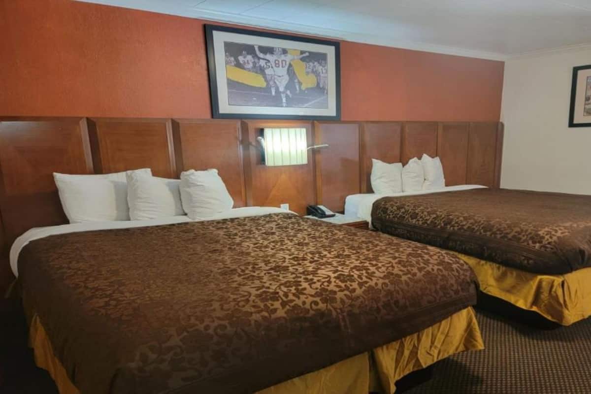 Une chambre d’hôtel avec deux lits, des têtes de lit en bois et un tableau encadré au mur.