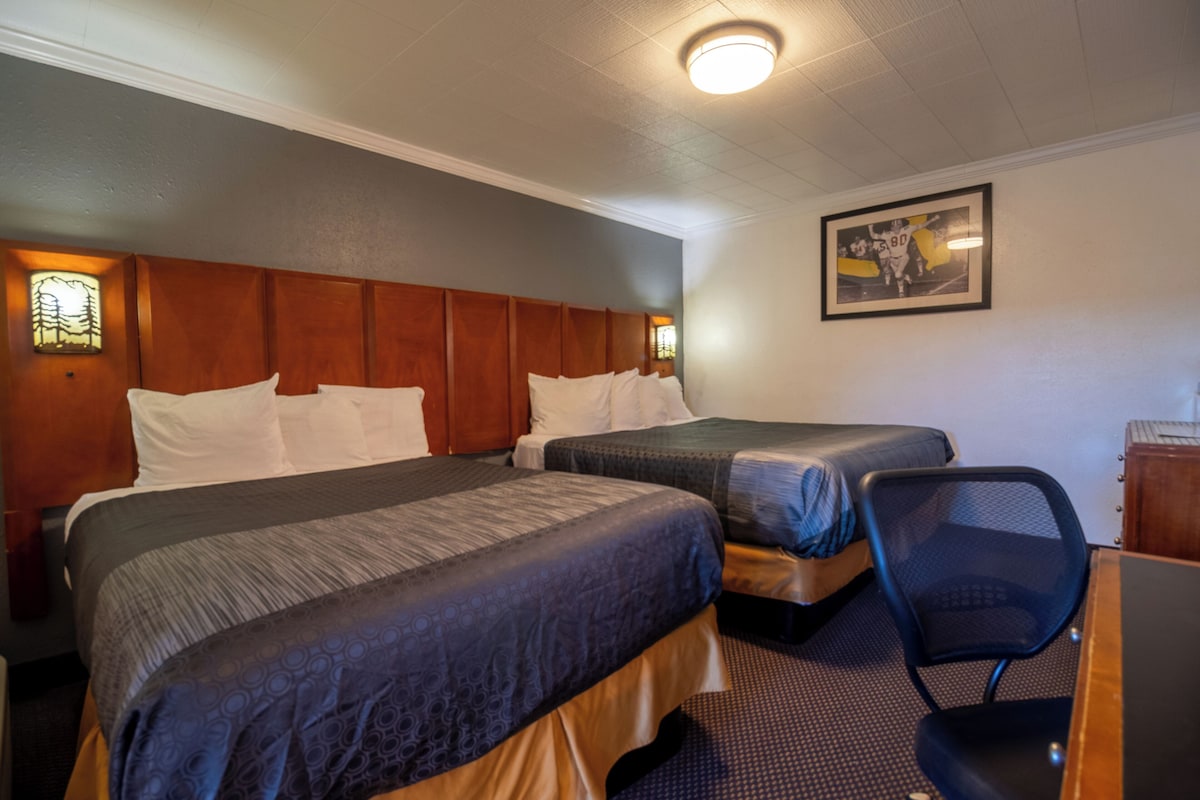 A hotel room with two beds, a desk, and a chair.