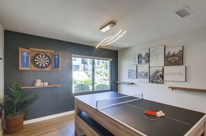 Une pièce équipée d’une table de ping-pong, d’un jeu de fléchettes et de tableaux encadrés accrochés au mur.