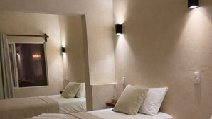 A hotel room with three beds, each with a beige blanket and pillows, and a window with curtains. - Chulel Hotel Origen (Mérida)