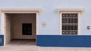 A building with a light blue facade, a white balcony with balusters, and a black door. - Chulel Hotel Origen (Mérida)