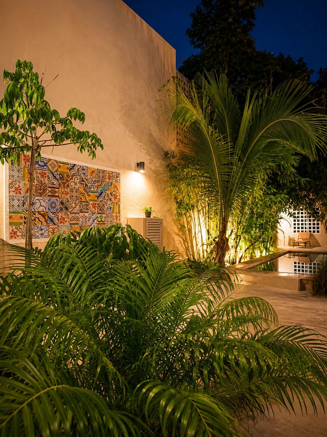 A courtyard with a tiled wall, palm trees, and a seating area.